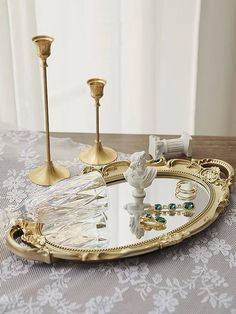 an ornately decorated tray with two candles and jewelry on it, sitting on a table