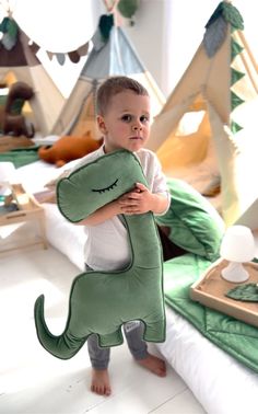 a young boy is holding a stuffed dinosaur