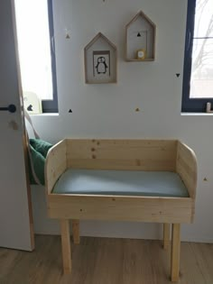 a wooden bench sitting in front of a window next to a wall mounted birdhouse