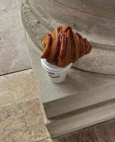 a croissant sitting in a cup on the ground