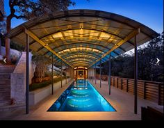 an indoor swimming pool in the middle of a building with a covered walkway leading up to it