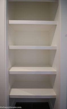 an empty white shelf in the corner of a room