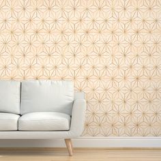 a white couch sitting in front of a wall with geometric designs on it's side