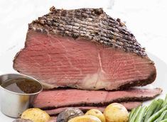 steak, potatoes and green beans on a white plate with seasoning in a small bowl