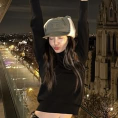 a woman with her arms up in the air, wearing a hat and black shirt