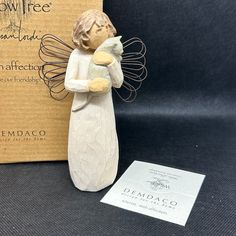 an angel figurine next to a cardboard box and business card on a table