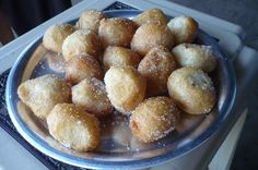 a plate filled with sugar covered donuts on top of a stove