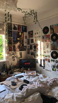 a messy bedroom with lots of pictures on the wall and bed sheets all over it