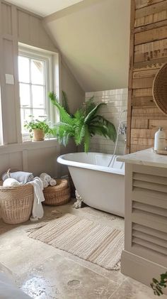 a white bath tub sitting under a window next to a plant in a basket on the floor