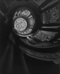 looking up at the top of a spiral staircase in black and white with intricate designs