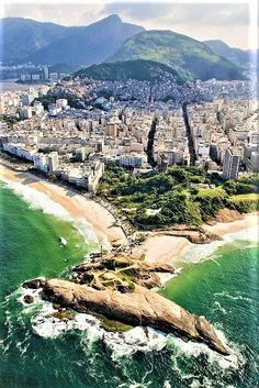 an aerial view of a city and the ocean with waves crashing on it's shore