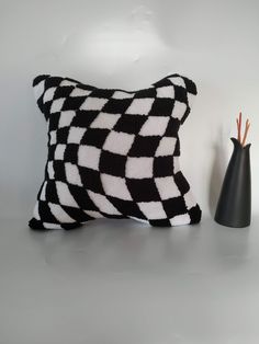 a black and white pillow sitting next to a vase