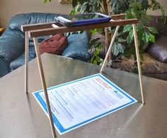 a table with a sign on it in front of a couch and potted plant