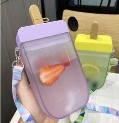 a person holding up a plastic container with strawberries in it and a lemon slice inside