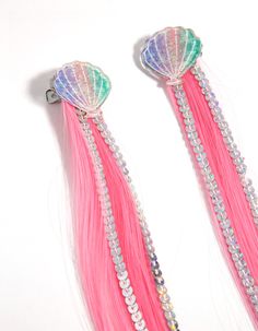 two pink and green hair with seashells attached to them