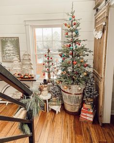 a small christmas tree in a bucket next to a window with other holiday decorations on it