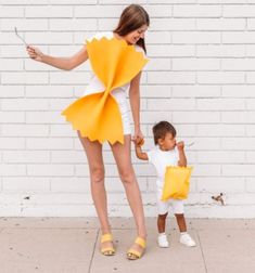 a woman holding the hand of a small child dressed as pikachu