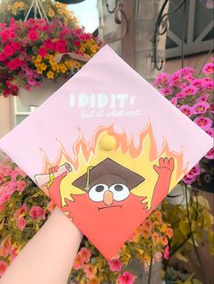 a hand holding up a pink graduation cap with an angry bird on it's side