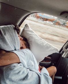 a man sleeping in the back seat of a car with his head on a pillow