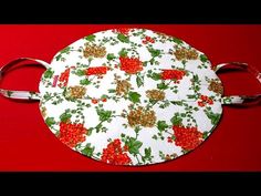 a round cutting board with holly and berries on it, sitting on a red surface