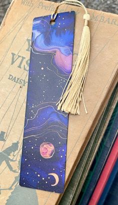 a bookmark with a tassel hanging from it's side on top of books