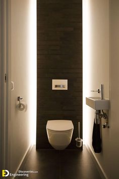 a bathroom with a toilet, sink and towel dispenser on the wall