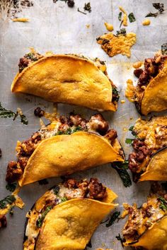 several tortilla shells with meat and cheese on a sheet of baking paper lined up