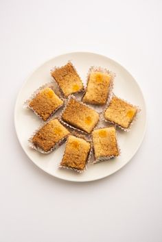 small pieces of cake sitting on top of a white plate next to an orange background