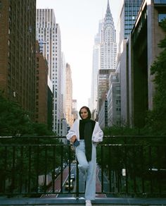 a woman standing on the sidewalk in front of tall buildings