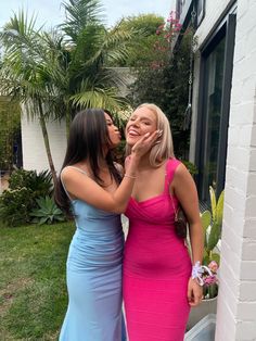 two women standing next to each other in front of a house