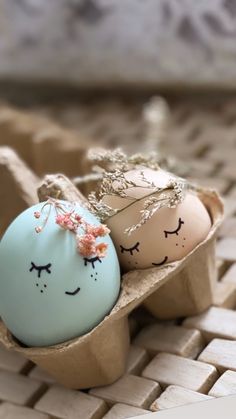 two decorated eggs sitting in an egg carton