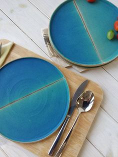 two plates with forks and spoons on top of a wooden cutting board next to each other