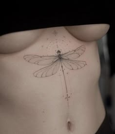 a woman's stomach with a dragonfly tattoo on it