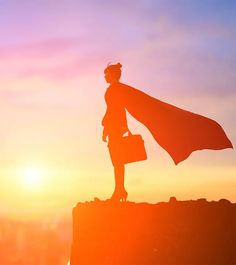 a woman standing on top of a hill with a briefcase in her hand and a cape over her head