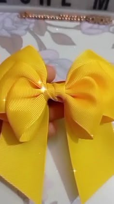 a hand holding a yellow bow on top of a table