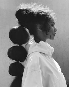 a black and white photo of a woman with her hair in a pony tail style