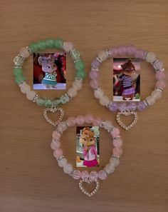 three bracelets with pictures on them hanging from a wooden wall next to a teddy bear