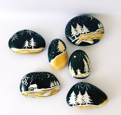 five painted rocks with trees on them and snowing in the night sky, set against a white background