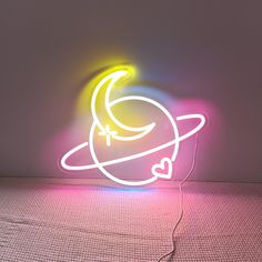 a neon sign that is sitting on the floor in front of a wall with a light coming from it