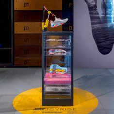 a display case with shoes in it on top of a yellow circular mat and a blue wall behind it