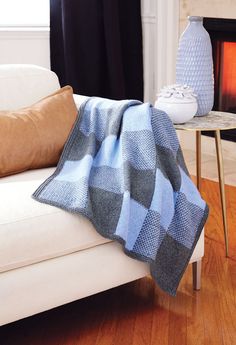 a couch with a blanket on it next to a table and a fire place in the background