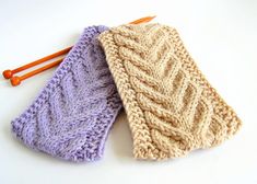 two knitted ties sitting next to each other on top of a white table with orange knitting needles