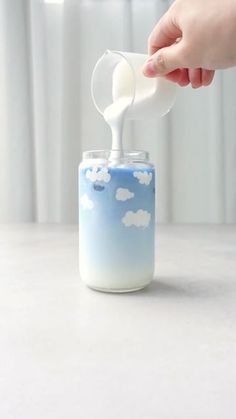 a person is pouring milk into a glass jar with clouds on the outside and inside