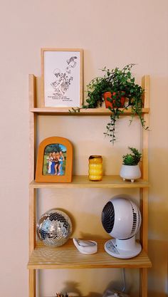 a wooden shelf with plants and pictures on it next to a wall mounted air conditioner