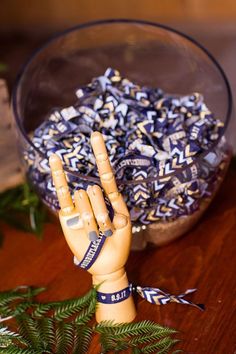 a wooden hand statue sitting on top of a table next to a bowl filled with blue and white confetti