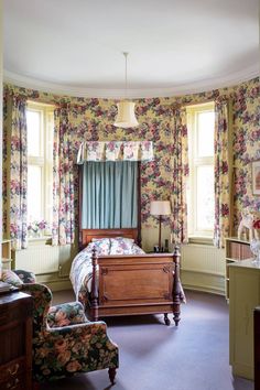 a bedroom with floral wallpaper and furniture