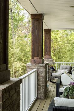 a porch with chairs and tables on the outside deck, looking out onto the woods