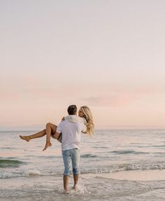 a man carrying a woman on his back while standing in the water at the beach