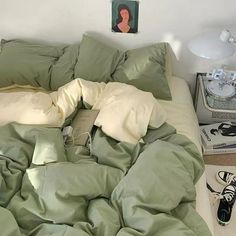 an unmade bed in a bedroom with green sheets and pillows on top of it