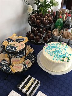 a table topped with cakes and cookies next to other desserts on top of a blue table cloth